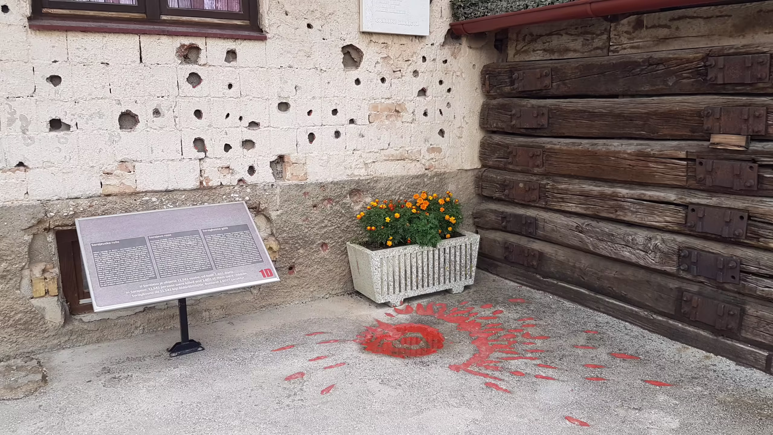 Damage to a building and a Sarajevo Rose on the ground.