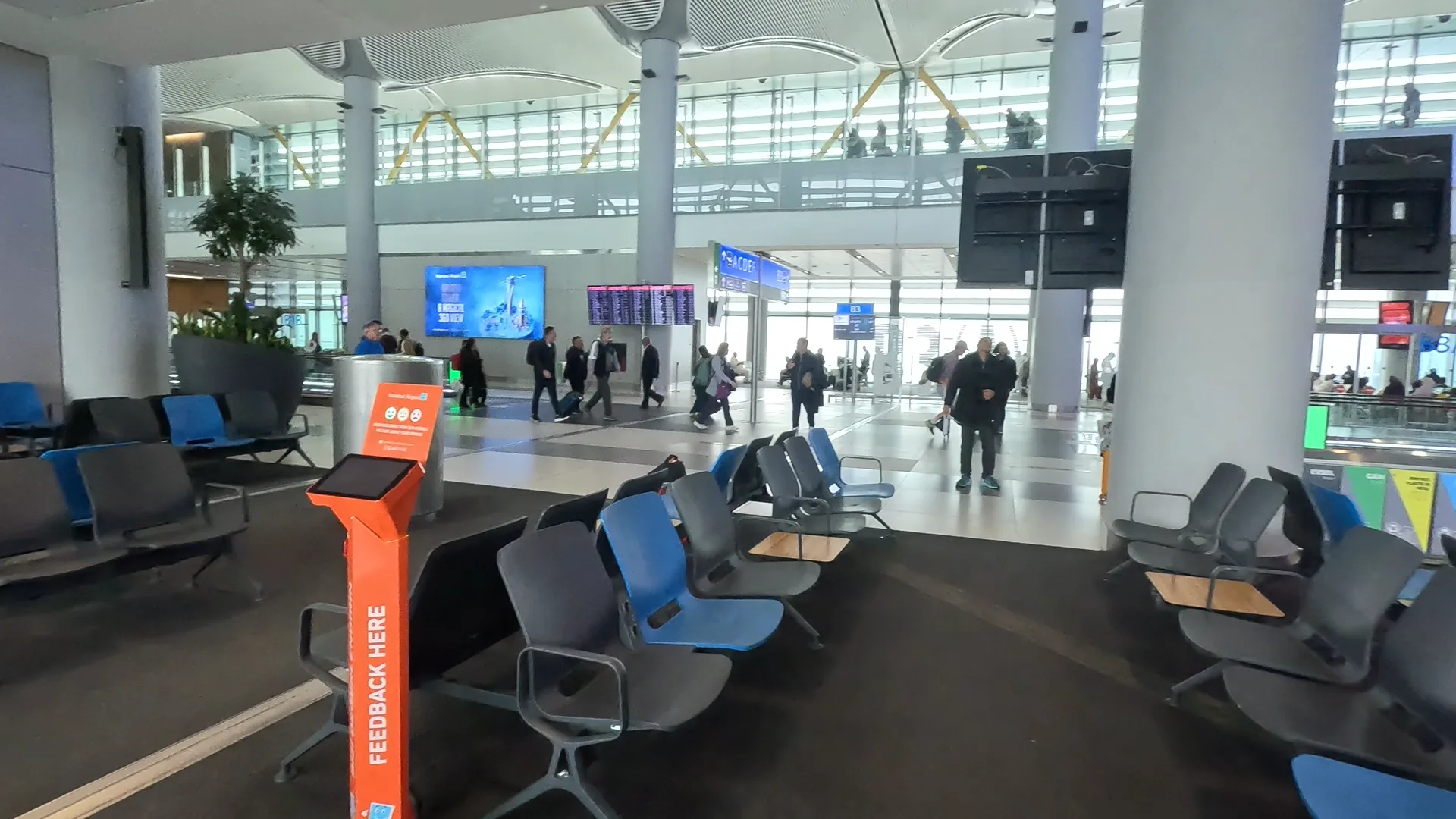 Seats at Istanbul Airport with passengers walking in the background.