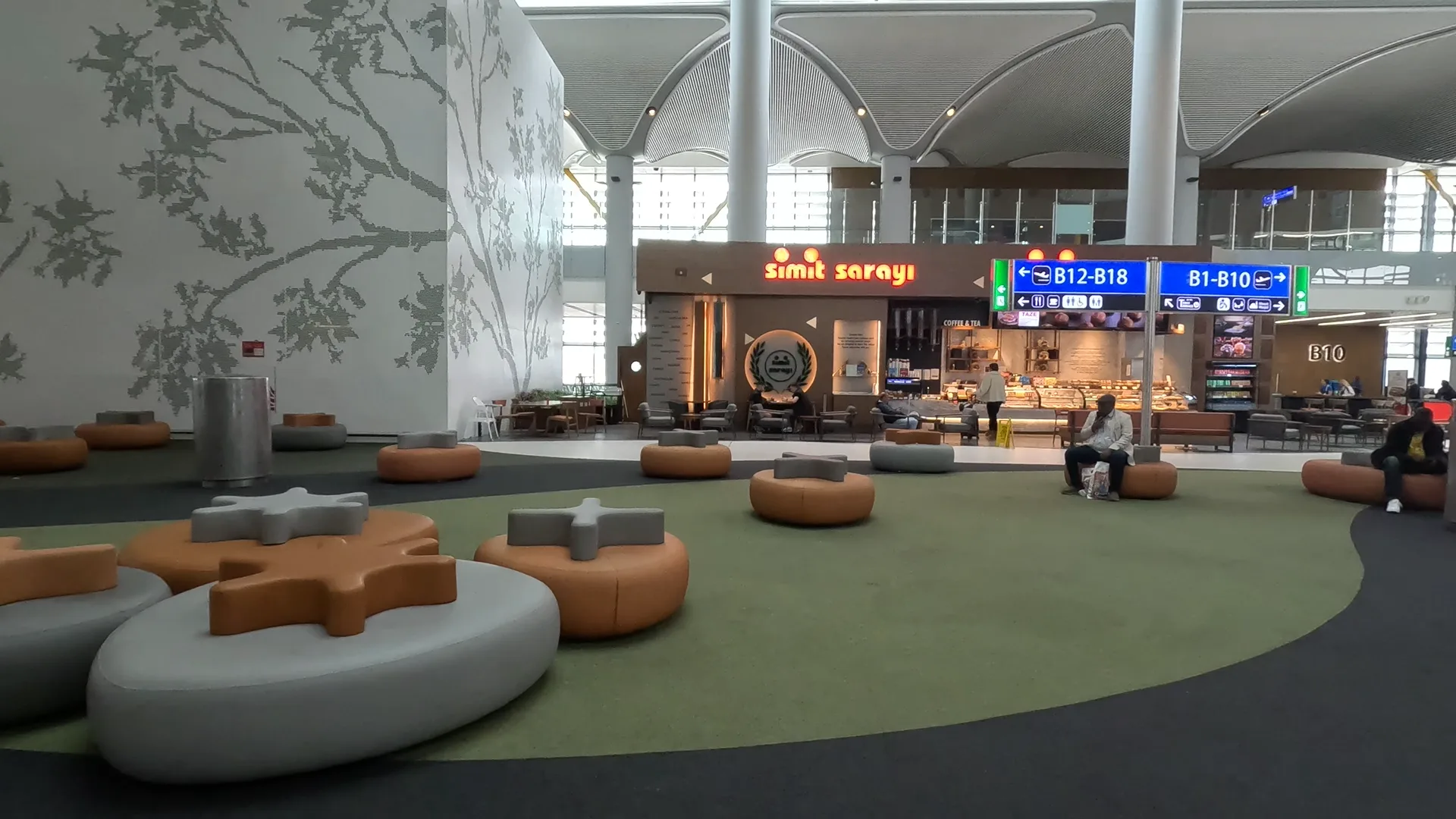 Padded seating at Istanbul Airport with Simit Sarayi cafe in the background.