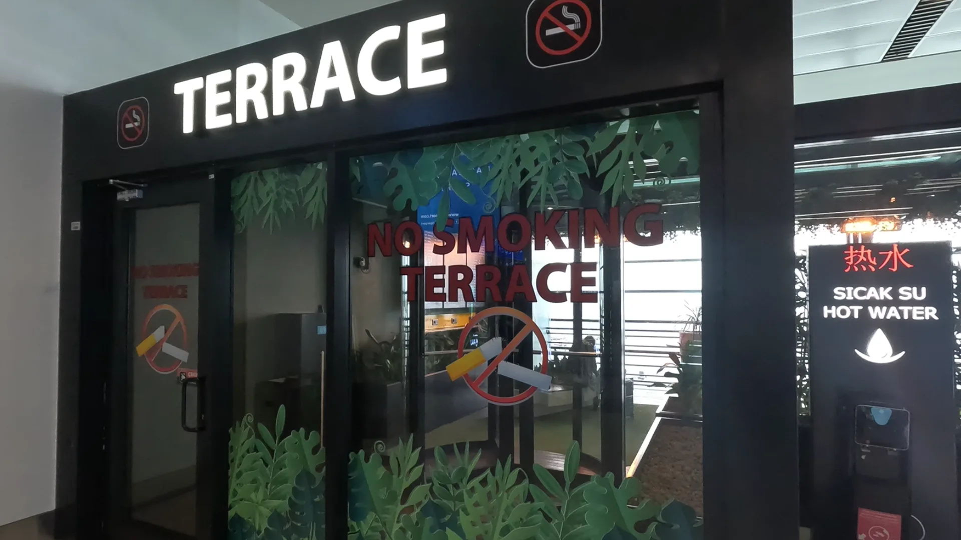 Glass windows with plants and benches - entrance to a Terrace at Istanbul Airport