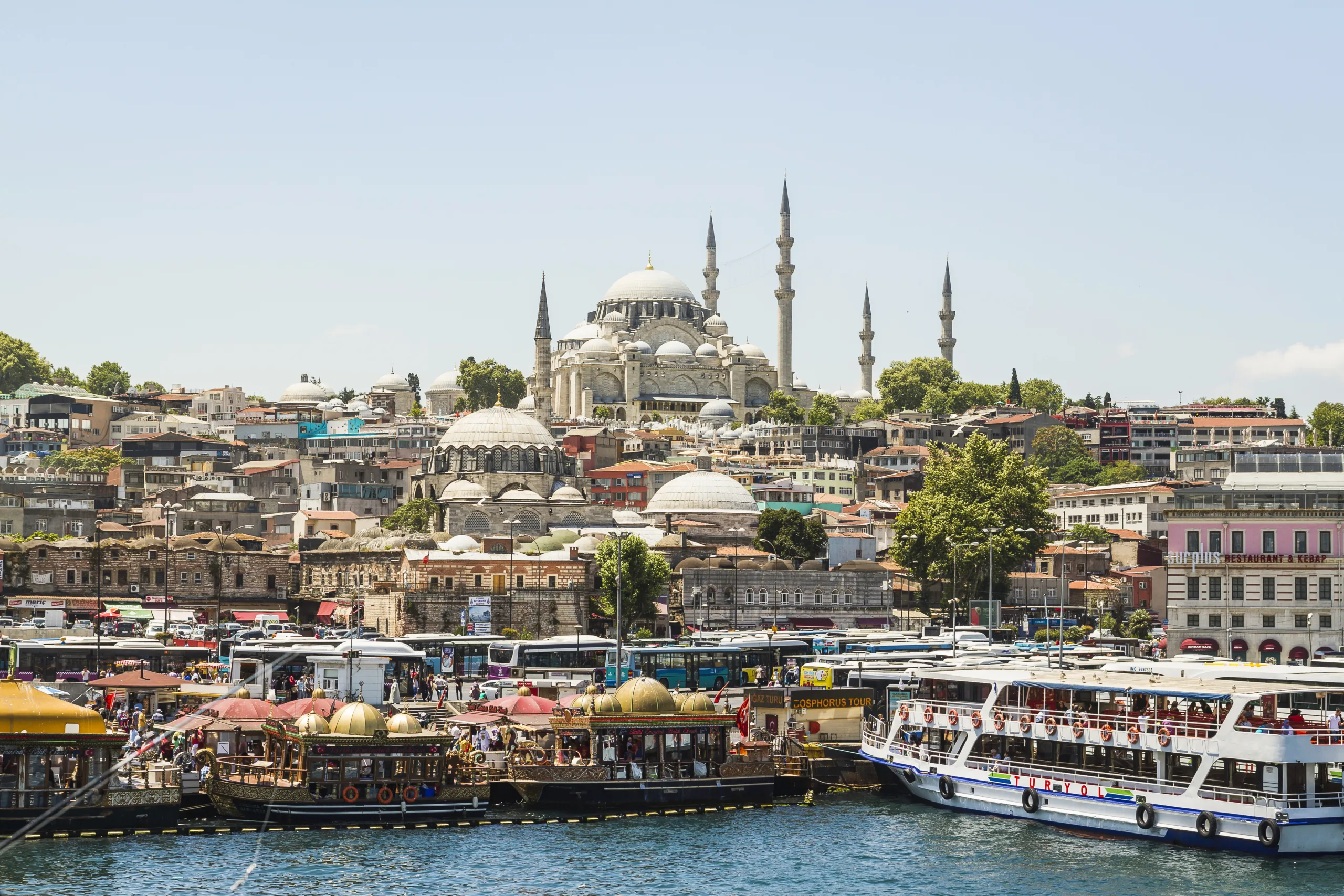 Bustling, colourful waterfront with market stalls and boats and the Süleymaniye Mosque, Istanbul.