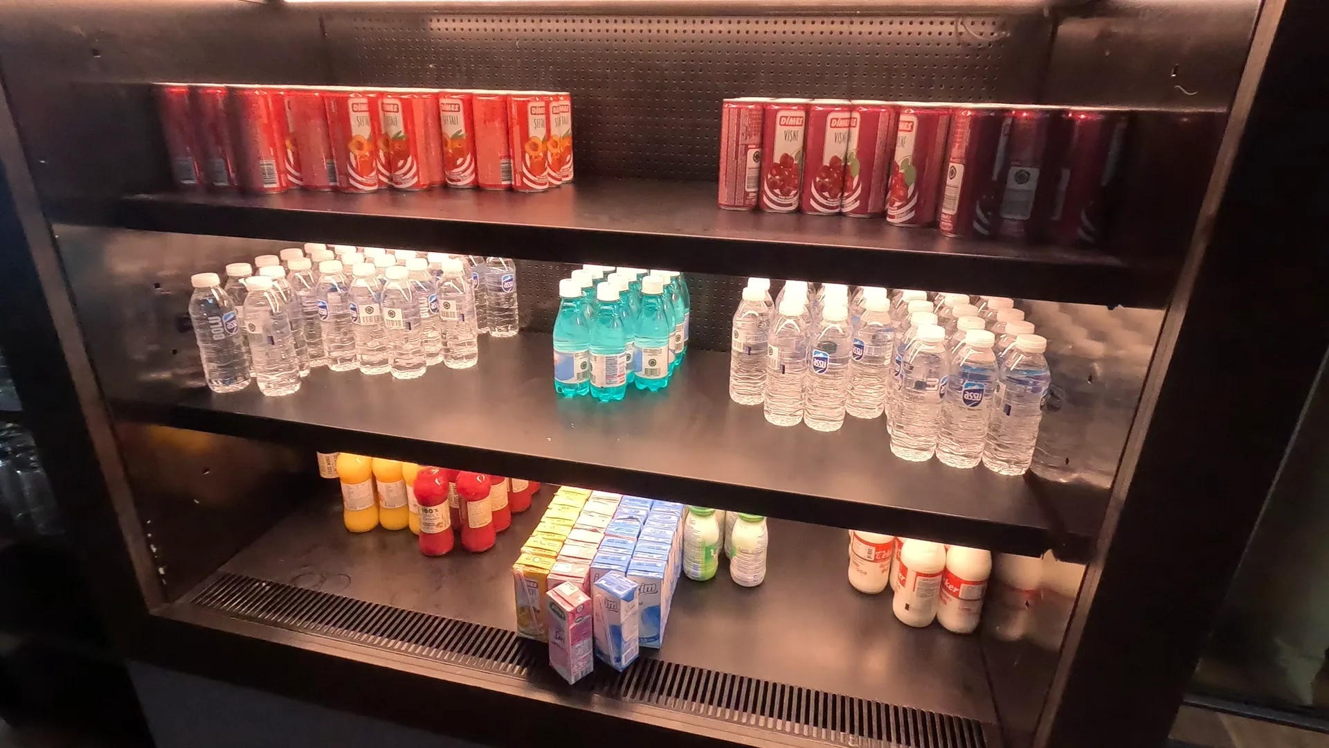 Fridge with bottles of still and sparkling water, carbonated drinks cans of various flavours, bottles of milk, and cartons of juice at Turkish Airlines Business Lounge, Istanbul Airport.