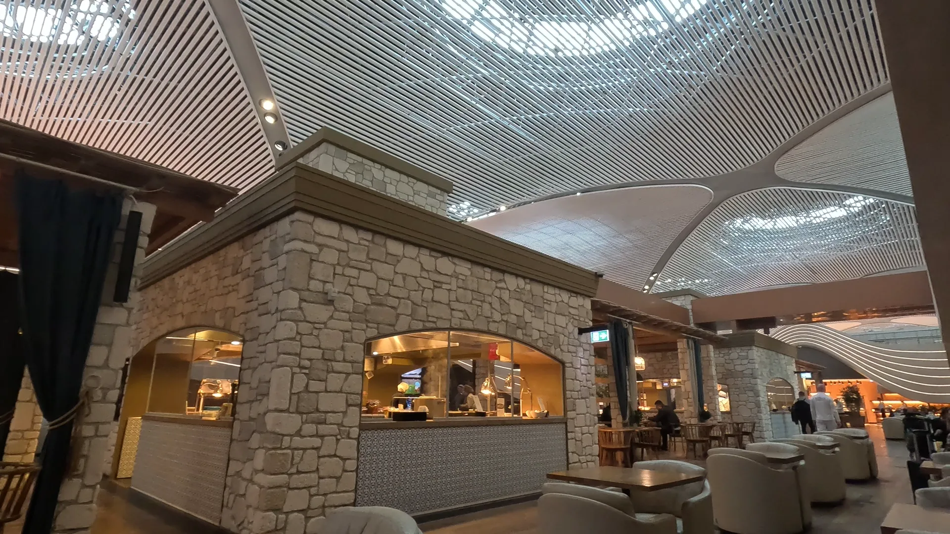 Many chairs and tables along with food stations where hot food is served, at Turkish Airlines Business Lounge, Istanbul Airport.
