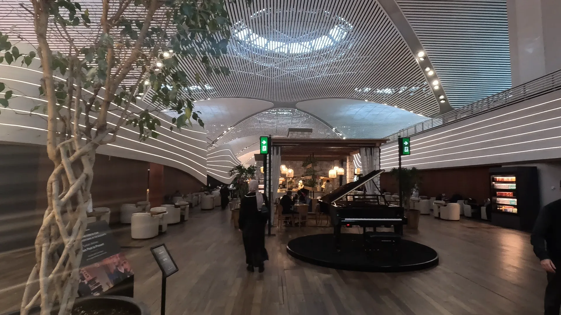 Piano, seats, tables and a food station at Turkish Airlines Business Lounge at Istanbul Airport.