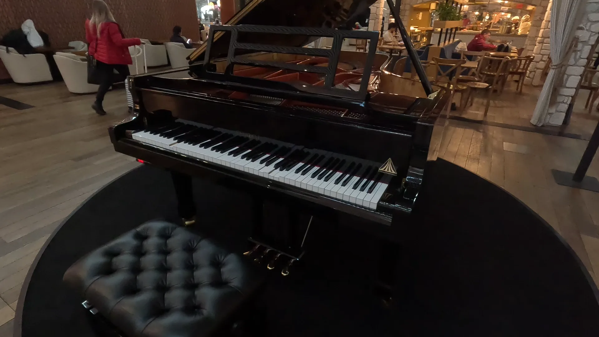 Stool, piano and seats/tables with chefs at work in a food station at Turkish Airlines Business Lounge, Istanbul Airport.